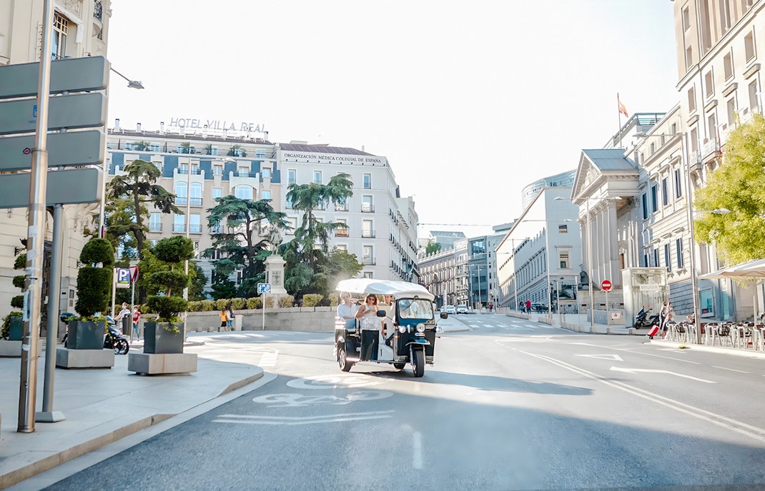 Electric tuk-tuk with tourists on a street near Hotel Villa Real, Madrid, Spain.