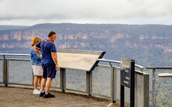 Tourists reading an information board overlooking the Blue Mountains, Australia.