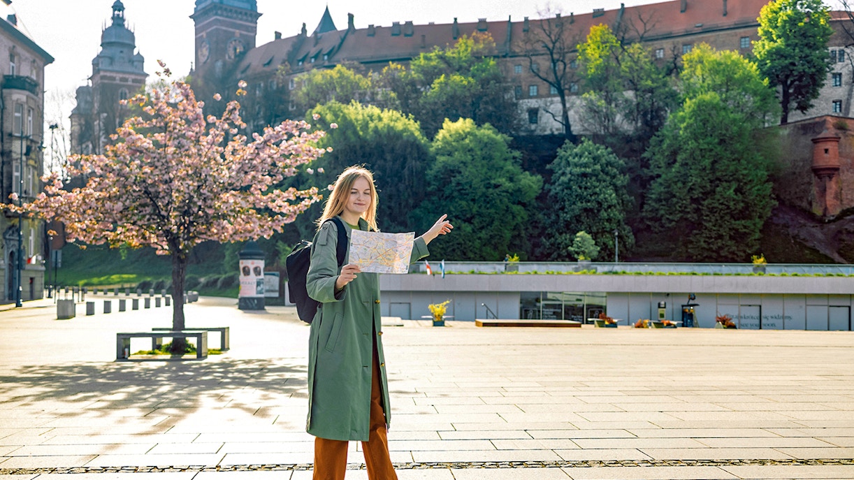 Tourist with map near Wawel Castle, Krakow, during guided tour.