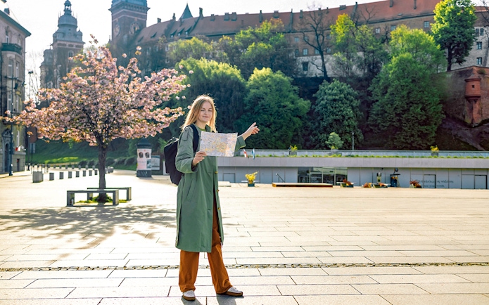 Tourist with map near Wawel Castle, Krakow, during guided tour.