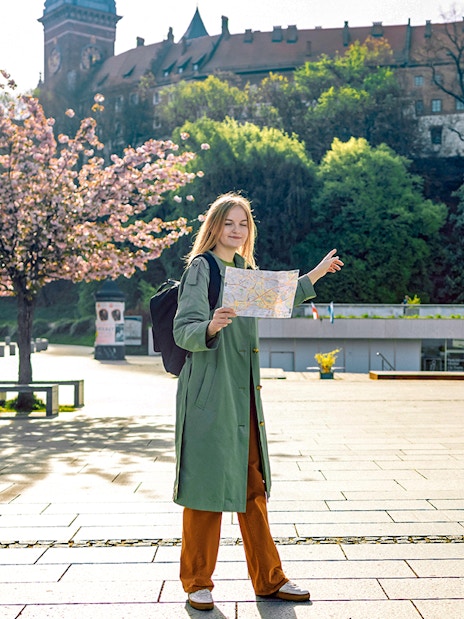 Tourist with map near Wawel Castle, Krakow, during guided tour.