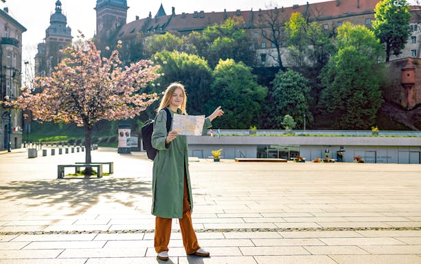 Tourist with map near Wawel Castle, Krakow, during guided tour.
