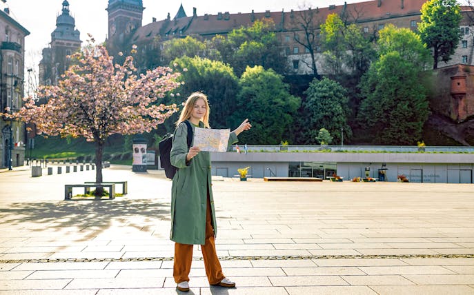 Tourist with map near Wawel Castle, Krakow, during guided tour.