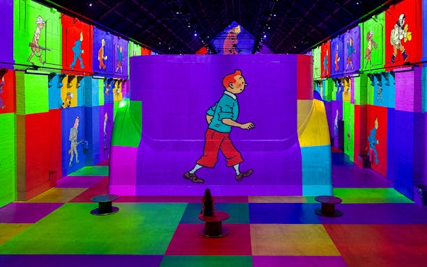 Guests viewing colorful Tintin projections at Fabrique des Lumières exhibition.