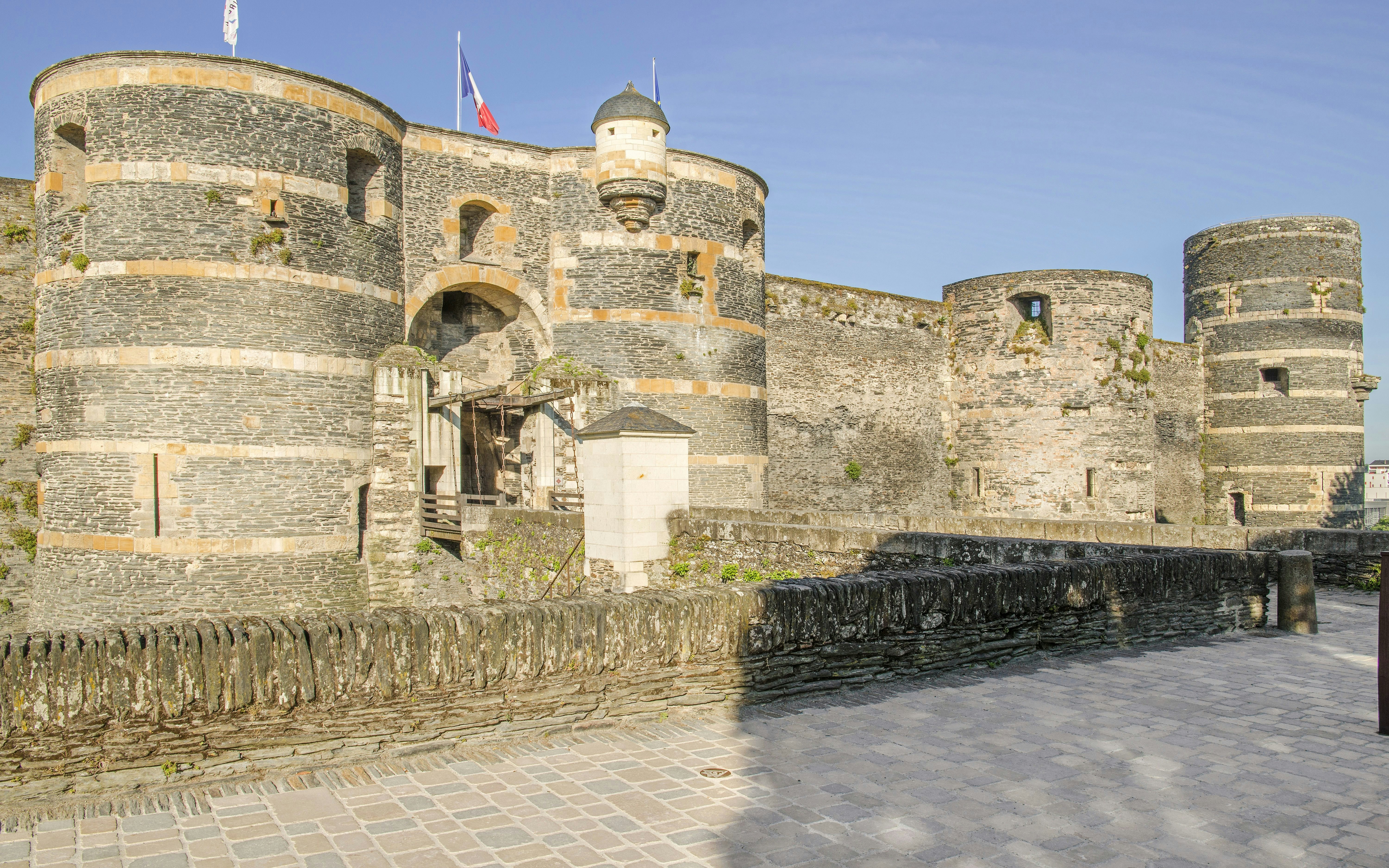 Château d’Angers stone fortress with round towers and French flag.