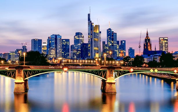 Frankfurt skyline at dusk with illuminated bridge during Evening Panorama Cruise.