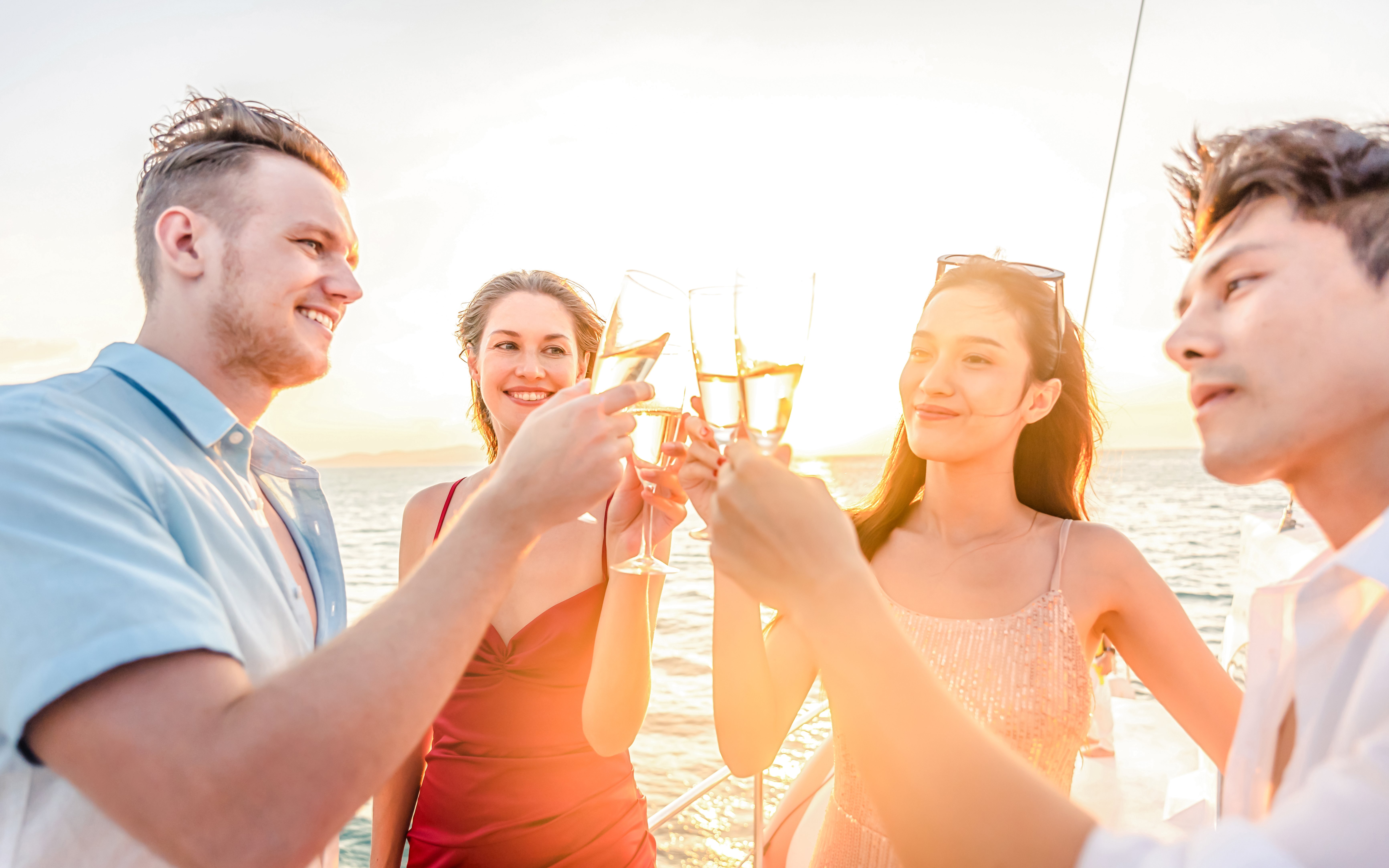 Friends toasting with champagne on a boat at sunset.