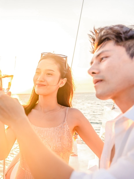 Friends toasting with champagne on a boat at sunset.