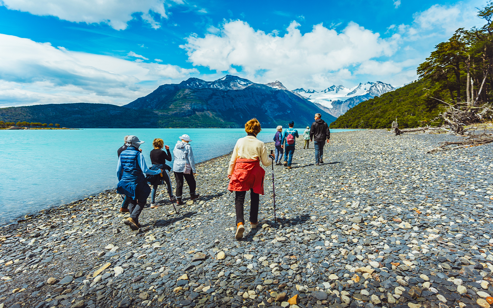 Hikers walking along the rocky shore of Argentino Lake in Los Glaciares National Park, Patagonia.