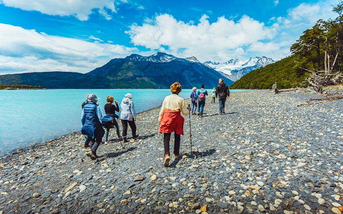 Hikers walking along the rocky shore of Argentino Lake in Los Glaciares National Park, Patagonia.