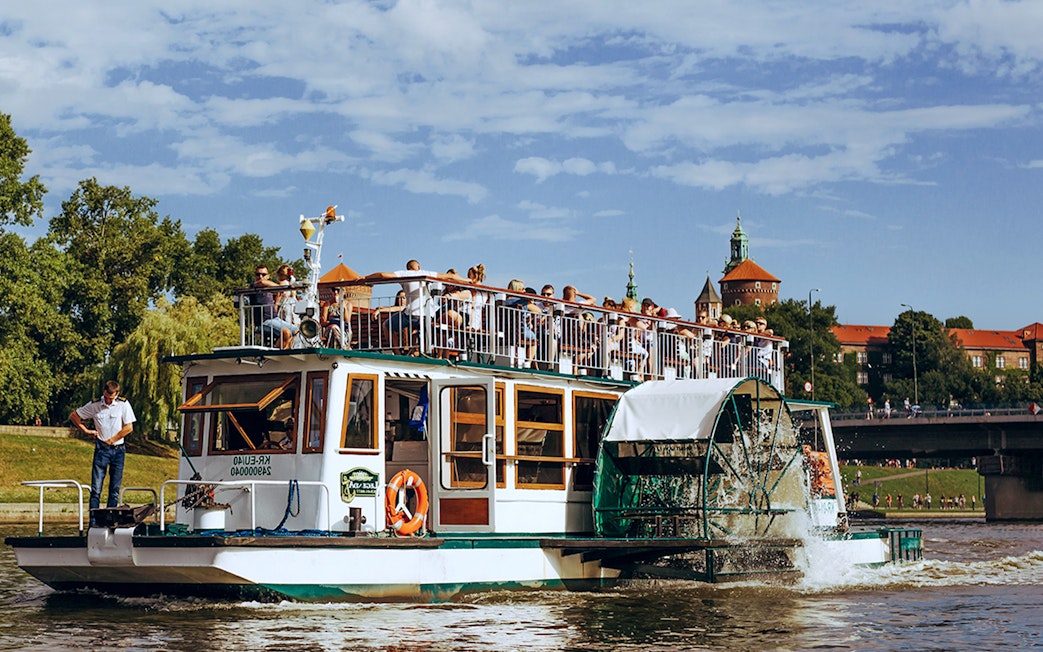 Cruise boat on the Vistula River with Wawel Castle in the background, Krakow.
