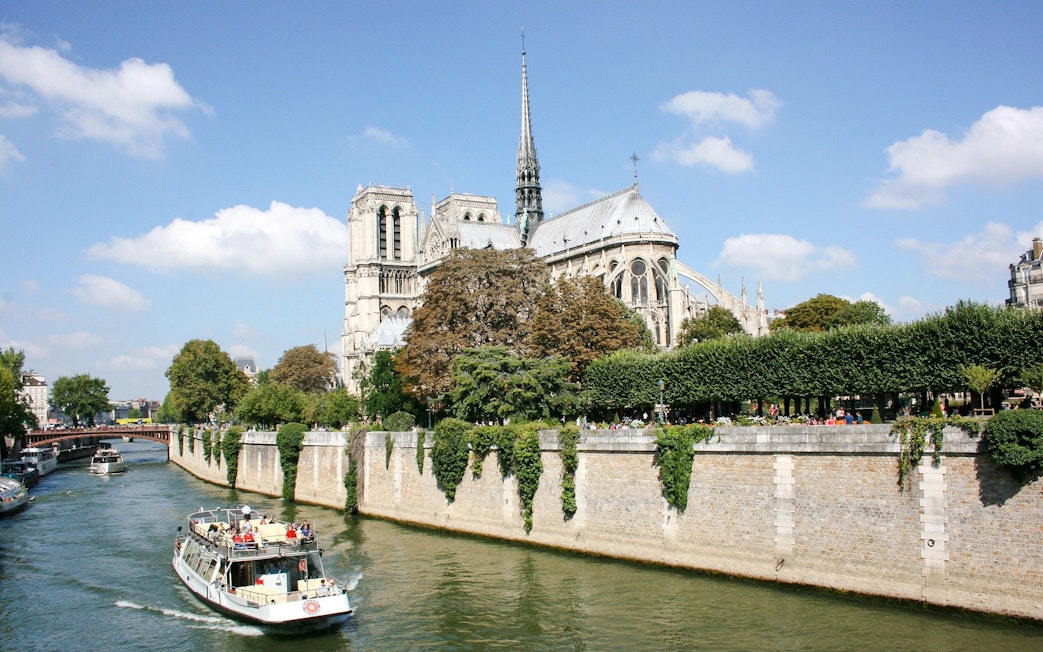 Seine River cruise boat passing Notre-Dame Cathedral in Paris, France.