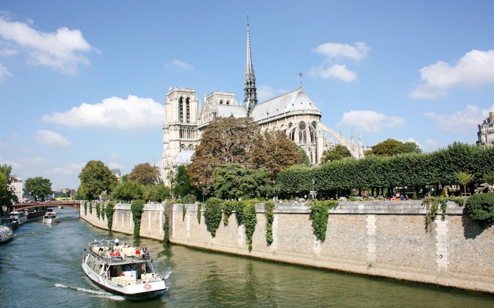Seine River cruise boat passing Notre-Dame Cathedral in Paris, France.