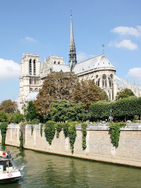 Seine River cruise boat passing Notre-Dame Cathedral in Paris, France.