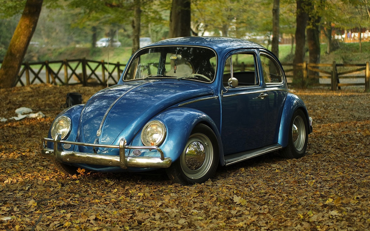 Vintage blue car parked in a forest setting, part of Etna wine tasting tour from Taormina.