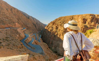 Traveler overlooking winding road through Todra Gorge cliffs, Morocco.