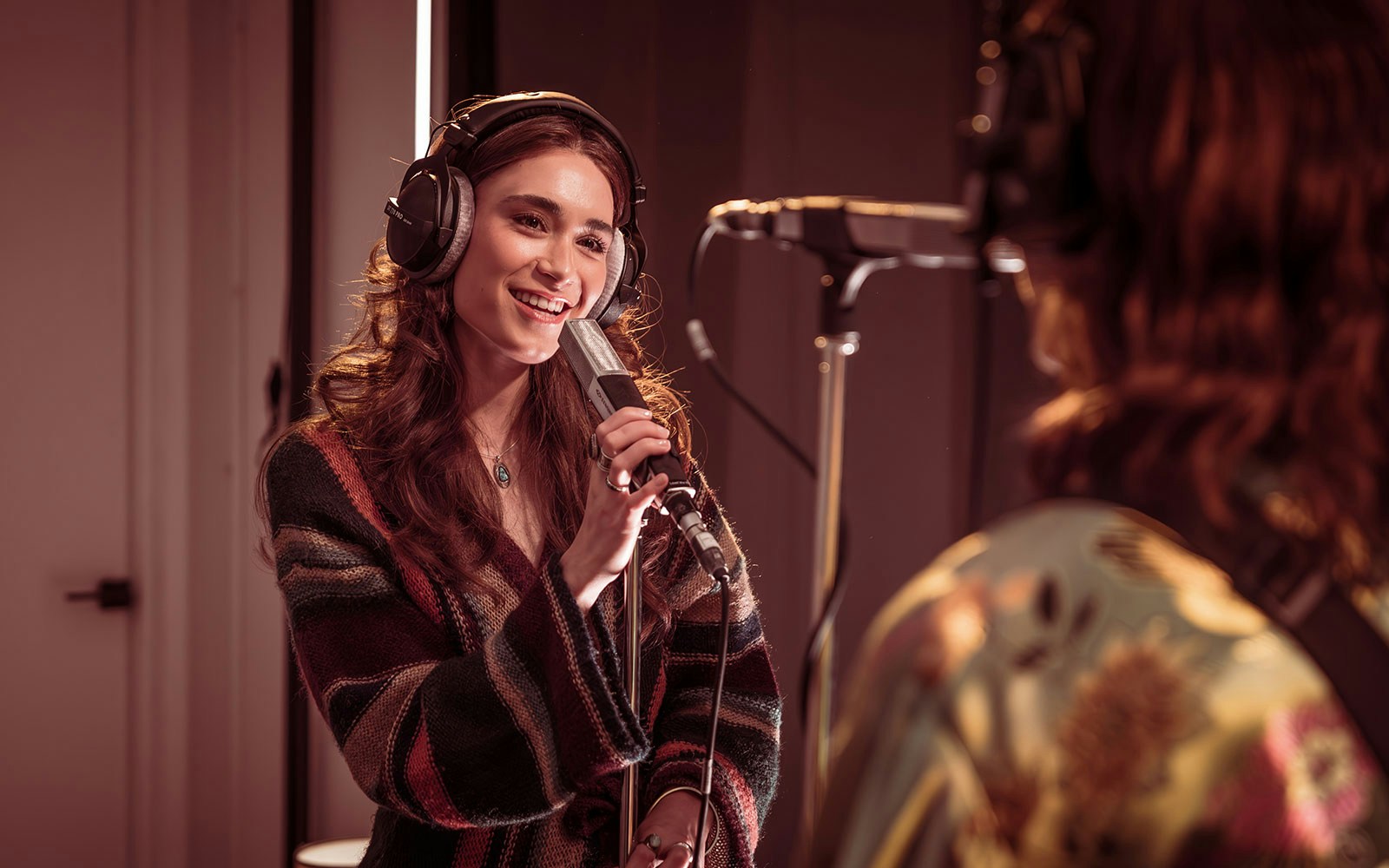 Singer recording in a studio with headphones and microphone, related to stereophonic experience.