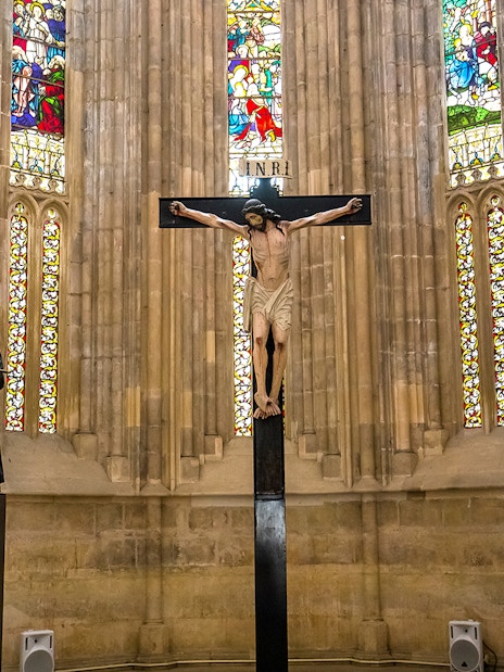 Crucifix and statues inside Batalha Monastery with stained glass windows.