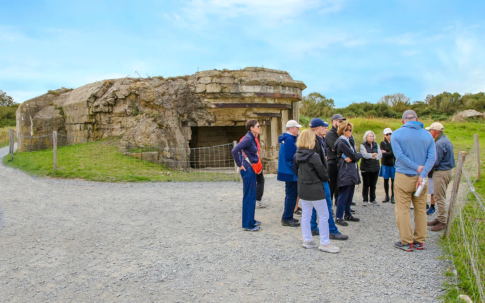 Tour group exploring Pointe du Hoc bunker site in Normandy, France.