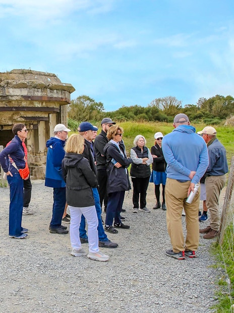 Tour group exploring Pointe du Hoc bunker site in Normandy, France.