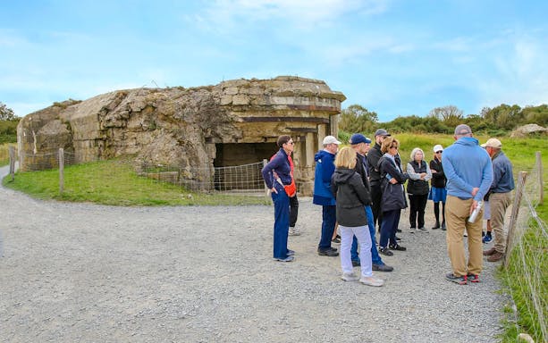 Tour group exploring Pointe du Hoc bunker site in Normandy, France.