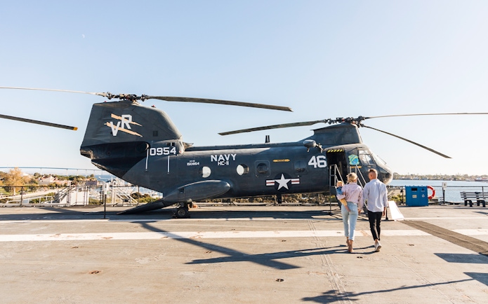 Family exploring a Navy helicopter on the USS Midway Museum deck, San Diego.