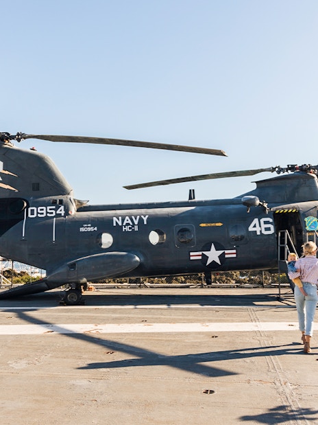 Family exploring a Navy helicopter on the USS Midway Museum deck, San Diego.