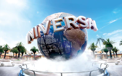 Universal Studios Japan globe with palm trees and clear sky.
