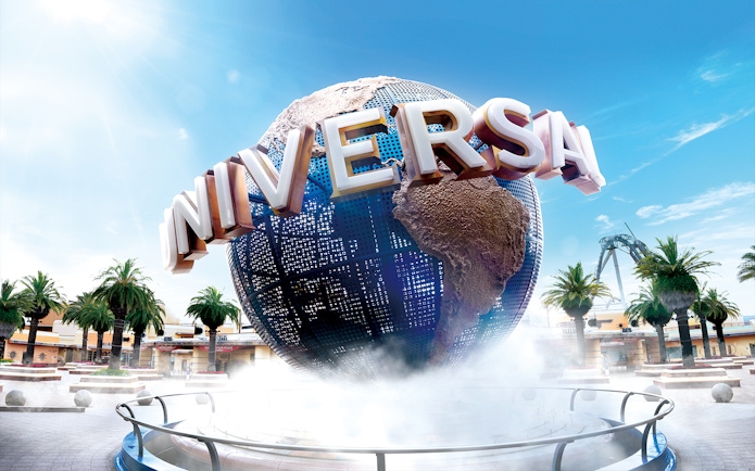 Universal Studios Japan globe with palm trees and clear sky.