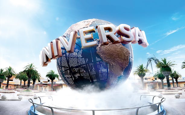 Universal Studios Japan globe with palm trees and clear sky.