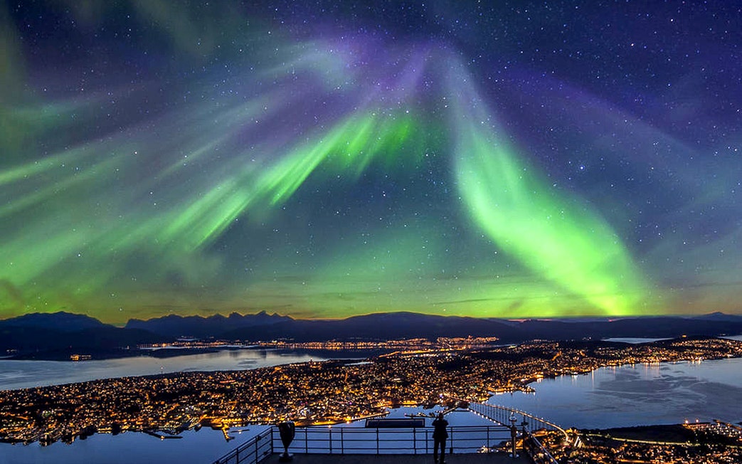 Northern Lights over cityscape during minibus tour in Norway.