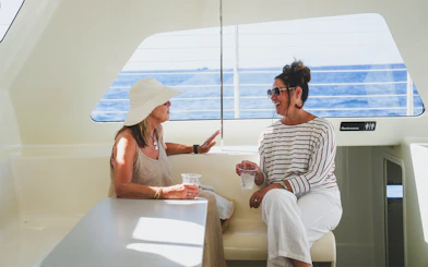 Women enjoying drinks on a Waikiki sailboat with ocean view.