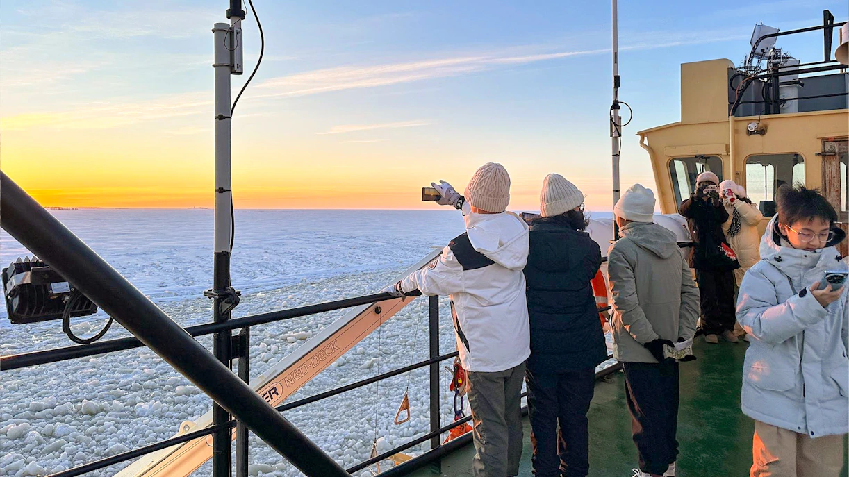 Tourists on Icebreaker Arktis cruise capturing sunset over frozen sea, Kemi.