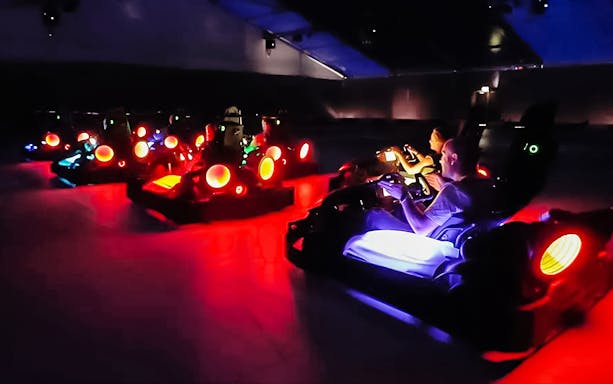 Participants racing in neon-lit karts at Chaos Karts Dubai indoor track.