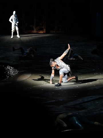 Performer on stage during La Perle show in Dubai, with dramatic lighting and acrobatic pose.