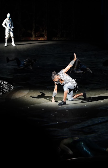 Performer on stage during La Perle show in Dubai, with dramatic lighting and acrobatic pose.