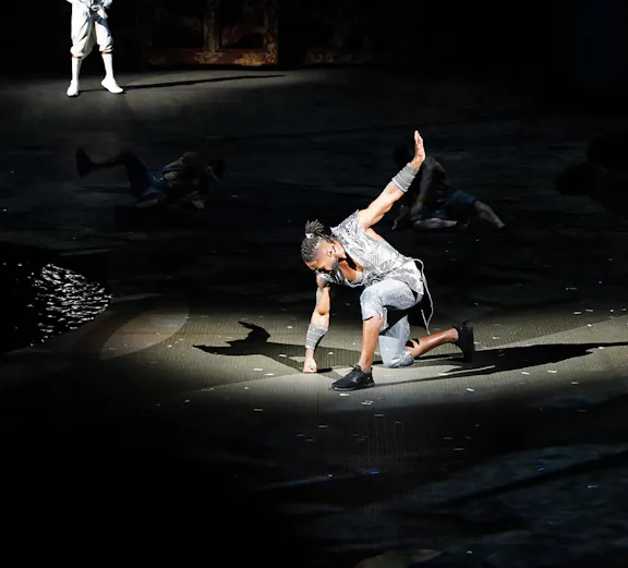 Performer on stage during La Perle show in Dubai, with dramatic lighting and acrobatic pose.