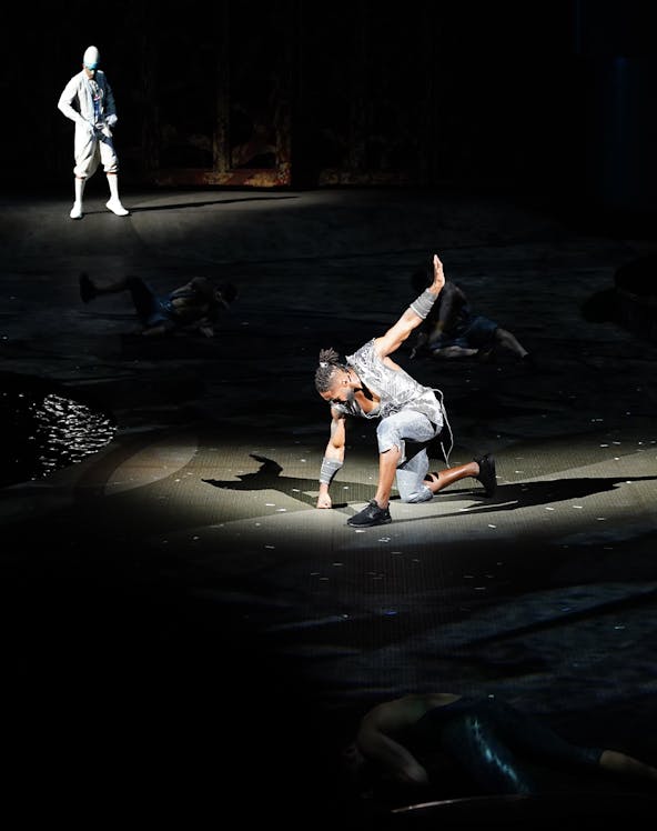 Performer on stage during La Perle show in Dubai, with dramatic lighting and acrobatic pose.