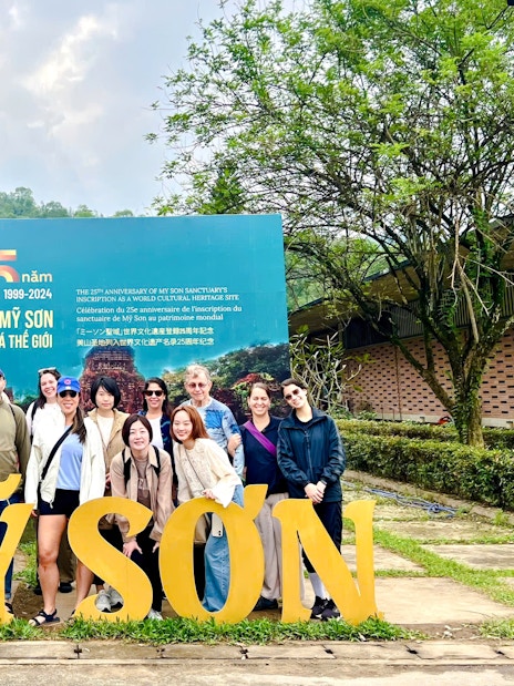 Tourists gathered at the entrance sign of Mỹ Sơn Sanctuary, Vietnam.