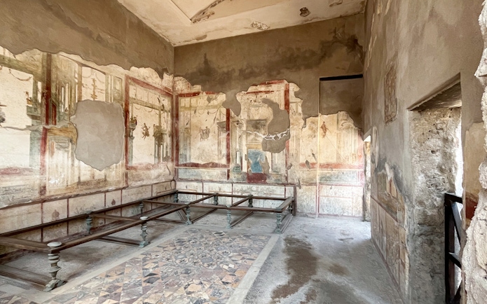 Herculaneum Ruins interior with ancient frescoes and stone benches.