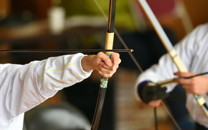 Lady practicing Japanese archery with focus on bow and arrow.