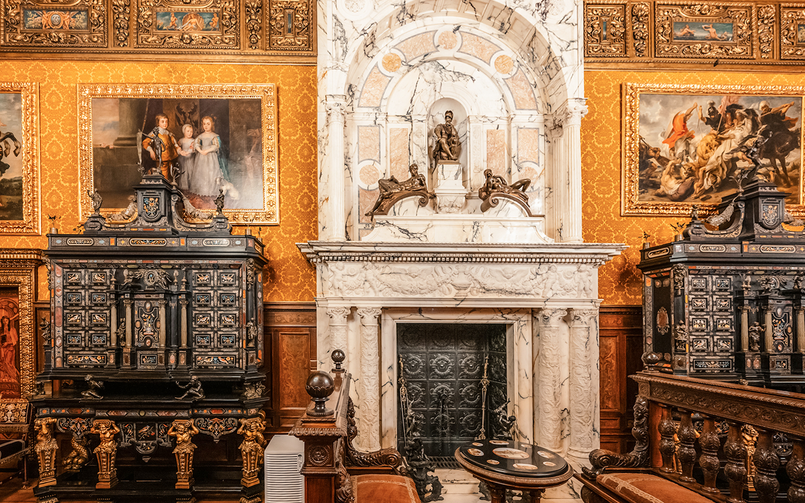 Historical royal room with ornate fireplace and paintings in Peles Castle, Romania.