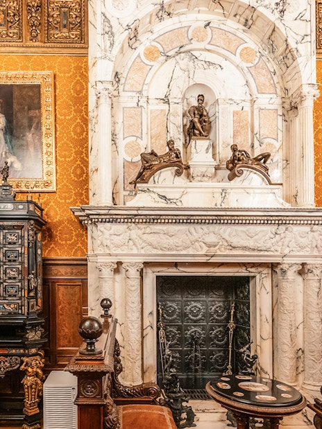 Historical royal room with ornate fireplace and paintings in Peles Castle, Romania.