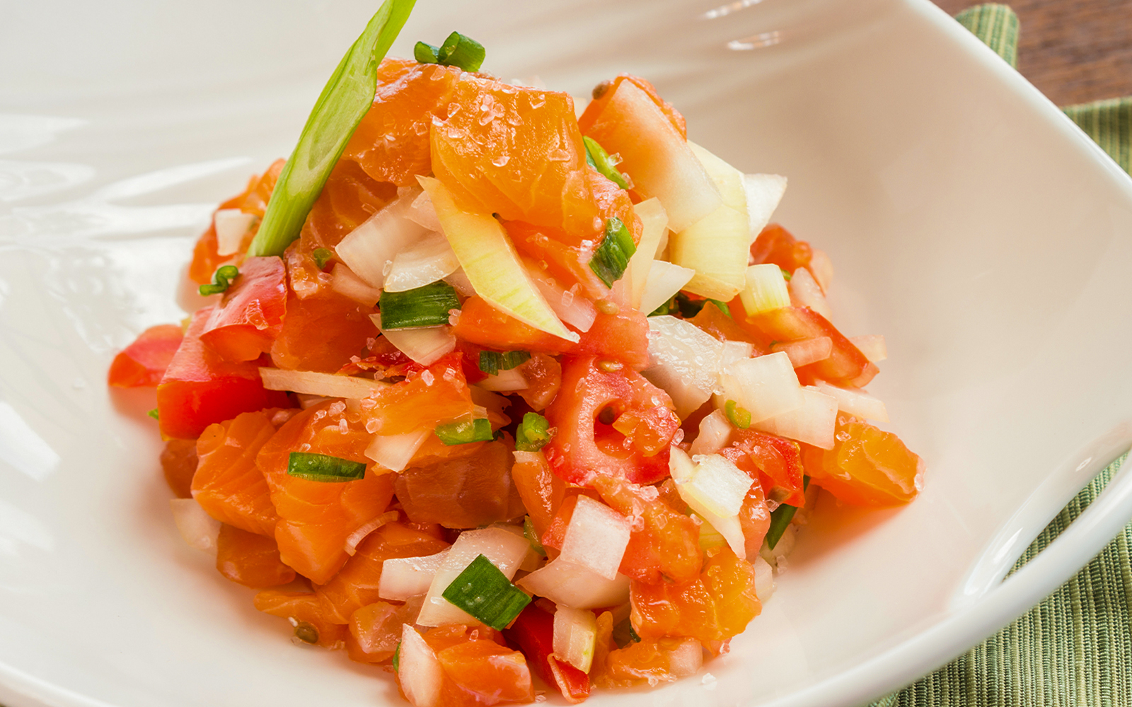 Lomi salmon with diced tomatoes and onions in a white bowl, traditional Hawaiian dish.