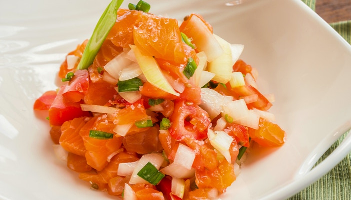 Lomi salmon with diced tomatoes and onions in a white bowl, traditional Hawaiian dish.