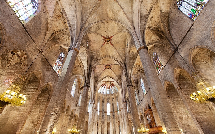 Interior view of Santa Maria del Mar's vaulted ceiling and stained glass windows in Barcelona.