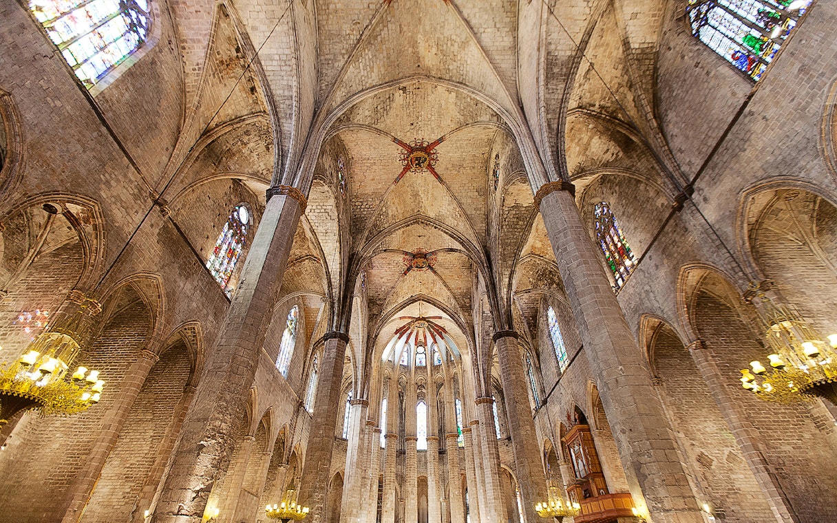 Interior view of Santa Maria del Mar's vaulted ceiling and stained glass windows in Barcelona.