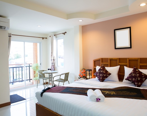 Hotel room interior with a king-size bed, modern decor, and large window view.
