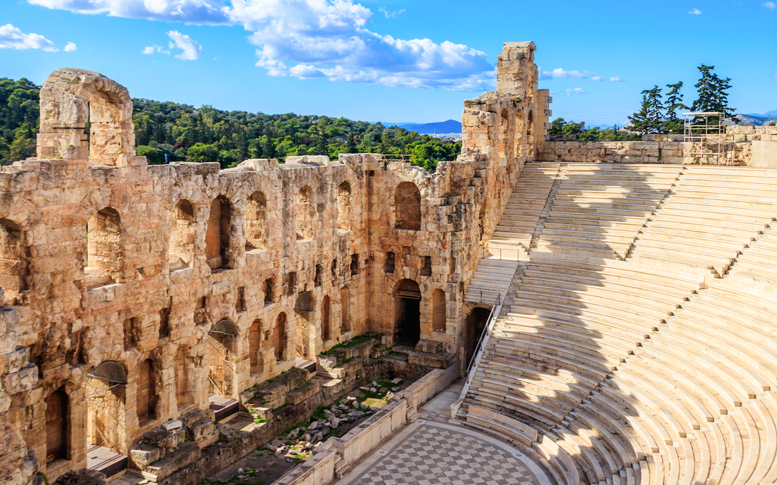 Odeon of Herodes Atticus in Athens with tourists exploring the ancient amphitheater.