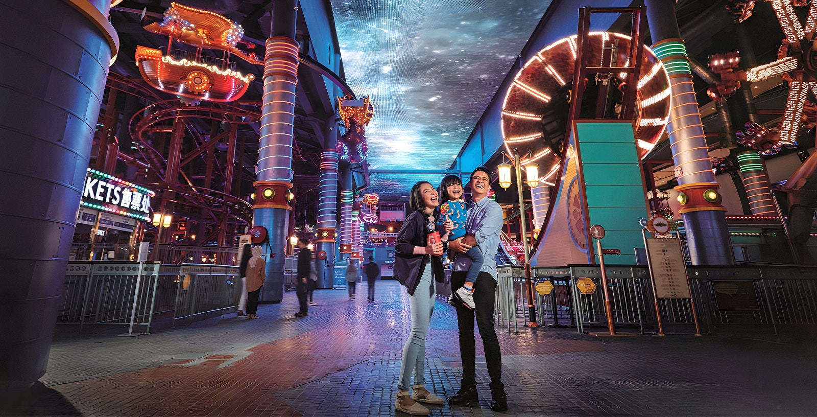 Family enjoying Genting Skytropolis Indoor Theme Park with vibrant lights and attractions.